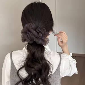 Großer brauner Haargummi mit Polka Dots aus Netzstoff, am Pferdeschwanz präsentiert.