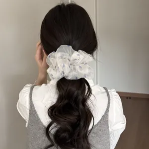 Großer weißer Netz-Haargummi mit blauen Punkten an einem Pferdeschwanz für das Haarstyling