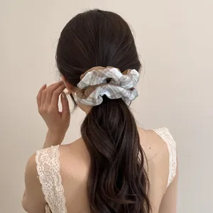Detail view of a Korean style brown and white striped bow scrunchie on low ponytail