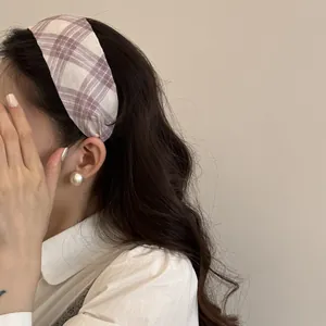 Close-up detail of a purple plaid wide-edge headband styled on a model's long wavy hair