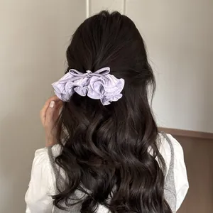 Vue arrière d'une femme aux cheveux ondulés portant une pince à nœud plissée violette