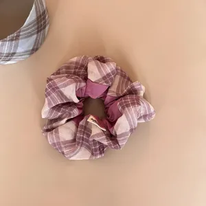 Detail view of a purple and beige plaid scrunchie with soft fabric texture