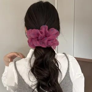 Nahaufnahme von übergroßem Himbeer-Mesh-Scrunchie mit blauen Punkten auf einem Pferdeschwanz
