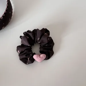 Κοντινό πλάνο λουλουδάτου scrunchie με ροζ βελούδινο αξεσουάρ σε σχήμα καρδιάς