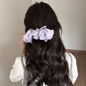 Vue détaillée d'une barrette à cheveux violette à volants et strass sur cheveux ondulés