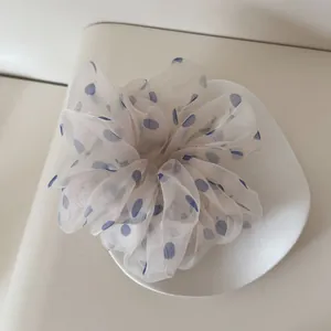 Nahaufnahme eines übergroßen weißen Mesh-Scrunchies mit blauen Punkten auf einem Teller
