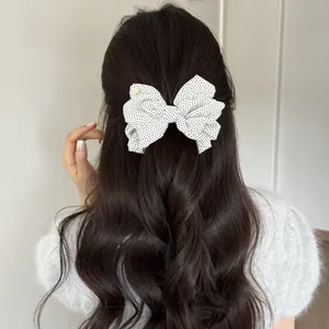 Detail view of a stylish retro polka dot bow banana clip styling long wavy dark hair