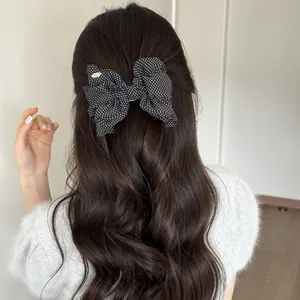 Back view of a polka dot bow banana clip on long wavy hair in Korean retro style.