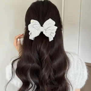 Back view of a white polka dot bow banana clip styled in long wavy hair