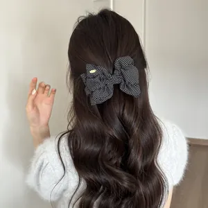 Detailed back view of a polka dot bow banana clip on long wavy brown hair