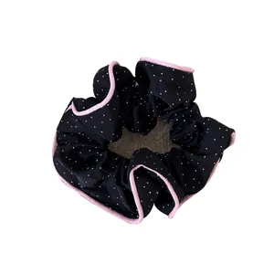 Elegant black polka dot hair scrunchie with pink ruffled edges for stylish ponytails