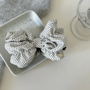 Macro view of a white polka dot bow banana hair clip displayed on a ceramic tray