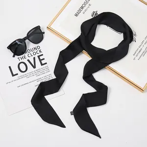 Vue détaillée d'un foulard en soie noir étroit utilisé comme ruban à cheveux ou pour sac chic