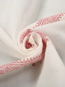 Close-up detail of white ethnic men's headscarf with intricate red printed patterns