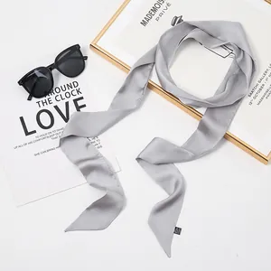 Élégante écharpe fine en soie grise présentée avec lunettes de soleil et magazines