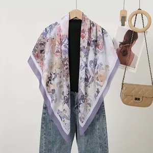 Elegant floral printed square scarf with laser-cut edges displayed with a beige bag