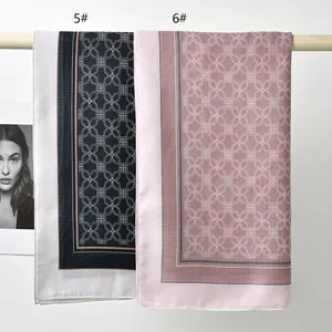 Detail view of two printed polyester square scarves with geometric patterns on a rod