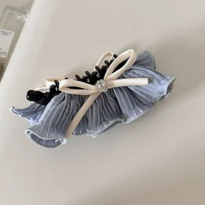Vue détaillée du tissu plissé bleu et du nœud en strass sur cette pince à cheveux élégante