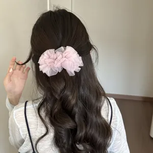 Pinza de pelo tipo banana con volantes de malla rosa en cabello castaño ondulado.