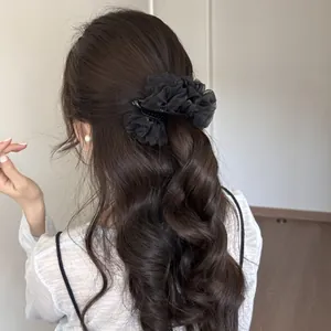 Vista detallada de una pinza de pelo de tul negro en cabello castaño ondulado