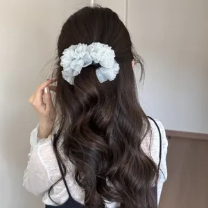 Vista trasera de mujer con cabello castaño ondulado y clip de banana de organza azul