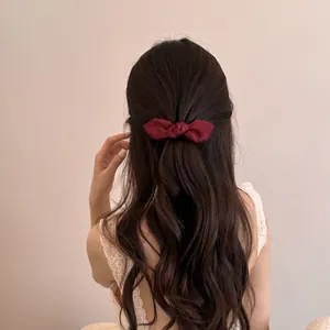 Elegant wine red bow hair clip for half-up hairstyle on model with wavy hair