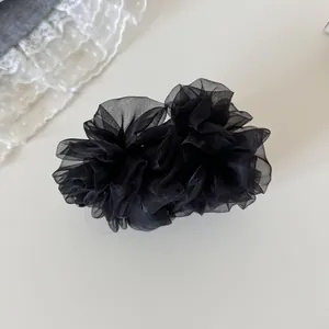 Vista detallada de un elegante clip de banana de malla negra con pliegues florales
