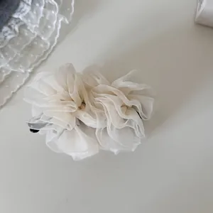 Vista detallada de la textura de malla rizada en este elegante pasador tipo banana blanco.