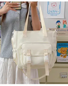 Vista detallada de una mochila escolar grande de color blanco roto sostenida por una modelo