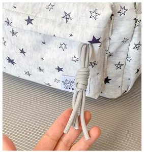 Close-up of star print backpack detail featuring a gray knotted zipper pull cord.