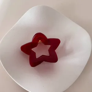 Detalle de una pinza para el pelo con forma de estrella granate semitransparente en bandeja