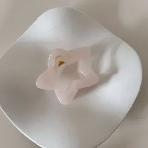 Vista detallada de una pinza para el cabello de estrella rosa claro con diseño calado en plato