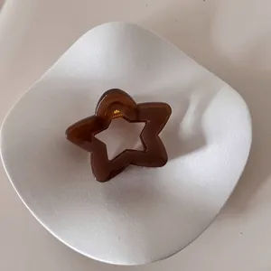 Elegante pinza para el cabello marrón con forma de estrella en un plato cerámico blanco.