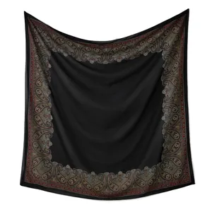 Vue détaillée d'un foulard carré en mousseline de cristal noir avec bordure paisley.