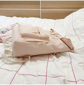 Side view of a lightweight pink travel backpack on a red grid bedsheet
