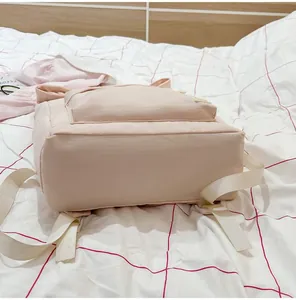 Bottom view of a minimalist pale pink casual travel backpack on a patterned bedspread.
