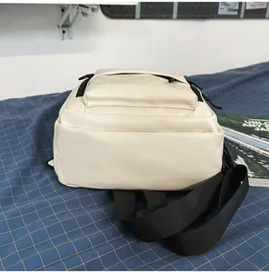 Detailed back view of a minimalist off-white PU leather backpack on a blue grid surface