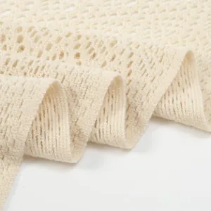 Detailaufnahme der Textur eines beigen gehäkelten durchbrochenen Strickschals aus Stoff