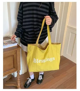 A woman carrying a large yellow nylon canvas tote bag with Blessings print indoor