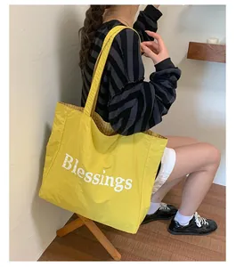 Large yellow nylon tote bag with white 'Blessings' text shown being carried by an Asian model.