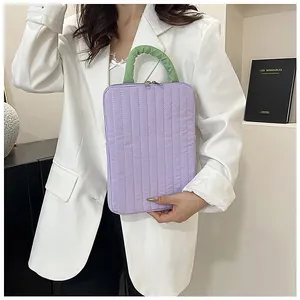Dettaglio di una borsa per laptop trapuntata viola con un manico a balze verde brillante