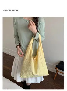 Close-up detail of a yellow nylon tote bag with flower embroidery held by a fashion model.