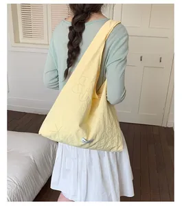 Close-up view of a light yellow nylon tote bag featuring delicate stitched flower patterns.
