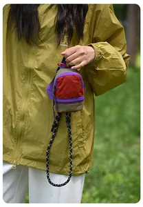 Outdoor detail view of a colorful dopamine style mini backpack pouch for coins and earphones