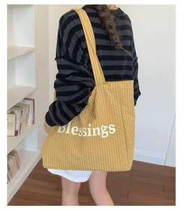 Detail view of a yellow gingham tote bag with Blessings print carried by a model