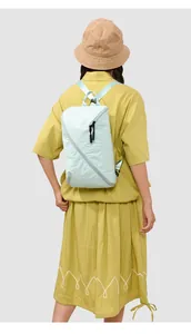Vue arrière d'un sac à dos minimaliste en nylon bleu clair porté par un mannequin en tenue
