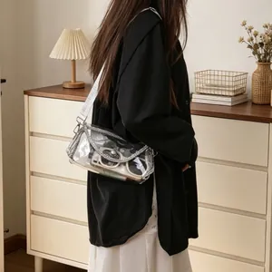 Lifestyle detail of a woman carrying a transparent PVC crossbody bag with chain detail.