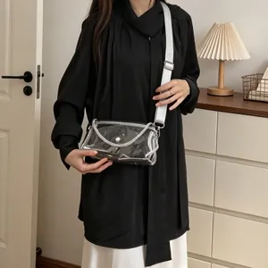 Detail view of a stylish transparent PVC crossbody bag with silver chain trim