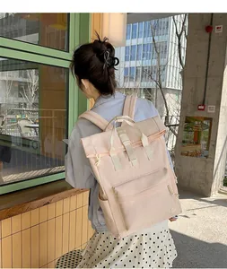 Close-up back view of a woman wearing a light pink minimalist roll-top backpack outdoors