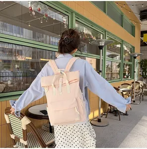 Minimalist light pink roll-top backpack for travel and leisure, lifestyle cafe view.